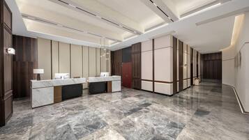 Un moderno vestíbulo de hotel con una recepción de mármol, paneles de madera oscura y un piso pulido.