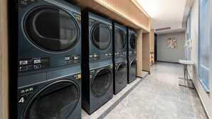 A row of black washing machines in a modern, well-lit laundry facility with a wooden ceiling and tiled floor. - Days Hotel By Wyndham Changsha Xingsha (Changsha)