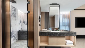 Un bagno moderno con un mobile vanitario in marmo, un ampio specchio e un lavabo integrato.