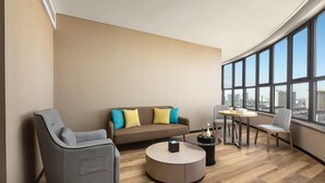 A modern living room with a sofa, armchair, coffee table, and a small table with books and a vase. - Days Hotel By Wyndham Changzhi Luzhou (Changzhi)