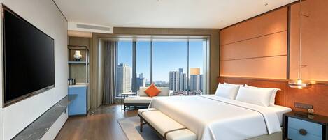 Habitación de hotel moderna con una cama grande, televisión de pantalla plana, escritorio y vistas a la ciudad.