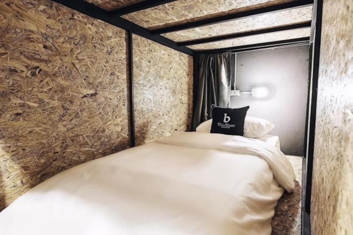 A bunk bed with a headboard, a pillow with a logo, and a light fixture above the bed.