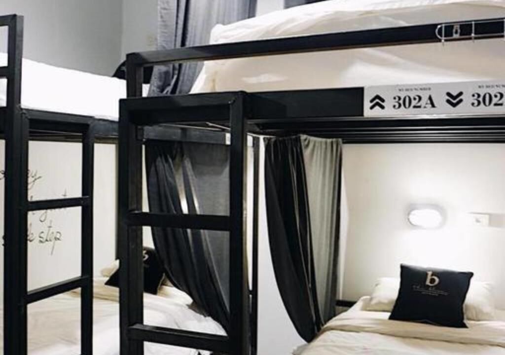 A bunk bed with a black frame, a white mattress, and a black pillow with a logo.