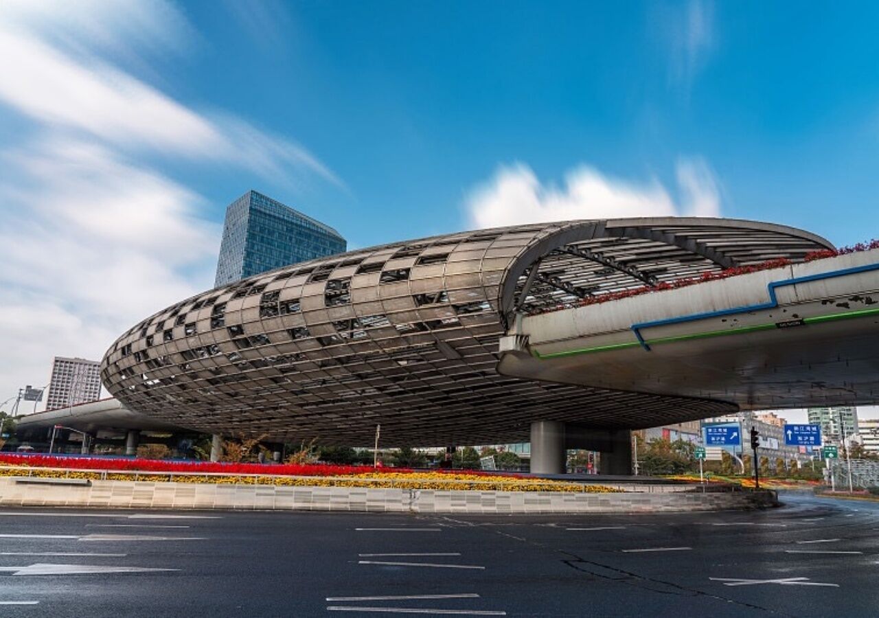 A modern architectural structure with a curved, metallic facade, situated in an urban setting with a clear sky.