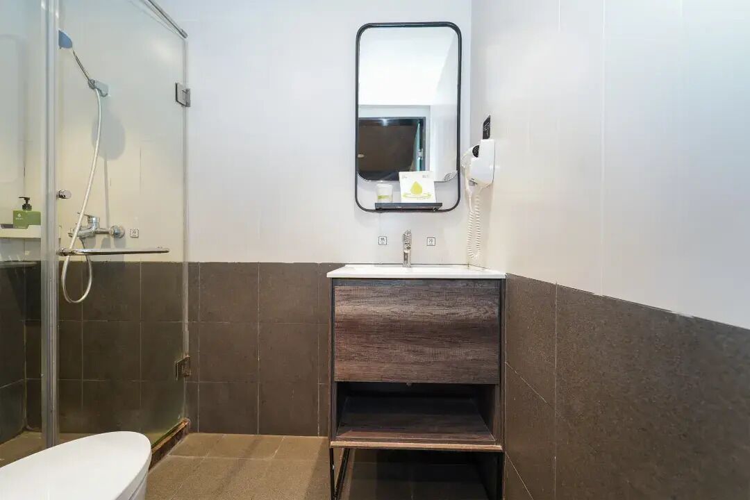 Un bagno con box doccia in vetro, lavandino bianco e specchio sopra.