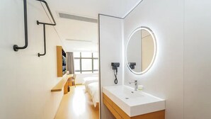 A modern hotel bathroom with a white sink, a mirror with a circular light, and a wooden vanity. - Jinglai Hotel ShanghaiWujiaochang Branch (Shanghai)