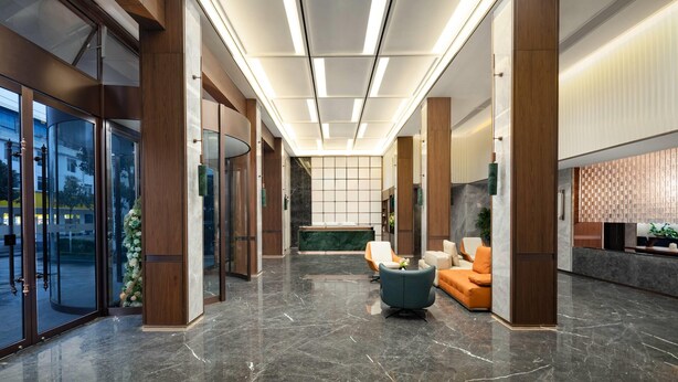 Un vestíbulo moderno con entrada de vidrio, un mostrador de recepción y una zona de estar.