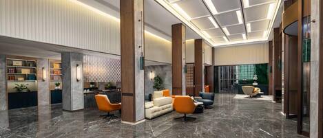 Eine moderne Lobby mit Marmorboden, Sitzbereichen und einer Rezeption.