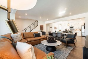 Ein modernes Wohnzimmer mit einem Ecksofa, einem Couchtisch und einem Essbereich mit Stühlen und einem Tisch.