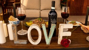 A table with a bottle of wine, glasses, a plate of food, candles, and decorative letters spelling 'LOVE' with a rose. - Top Floor Suite +Pool +Private Path to Shore, A/C. Accessible step-less layout (San Pedro Pochutla)