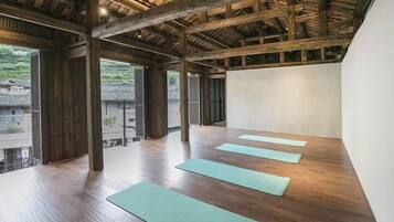 A spacious room with wooden beams and a sloped ceiling, featuring four yoga mats aligned for practice.