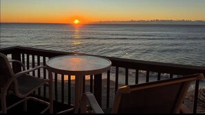 Sonnenuntergangblick von einem Balkon mit einem runden Tisch und Stühlen.