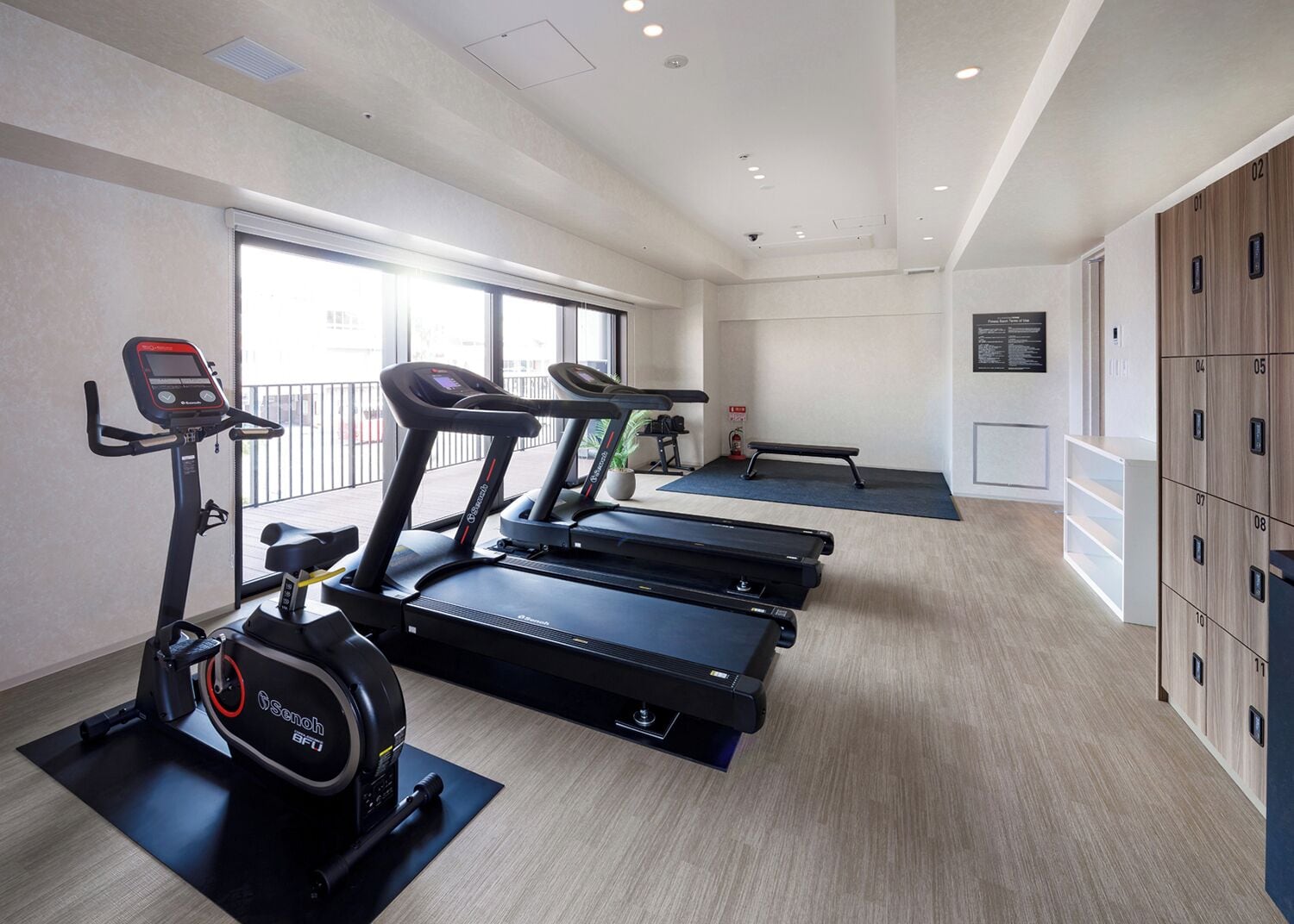 Un gimnasio con cintas de correr, una bicicleta estática y un banco.