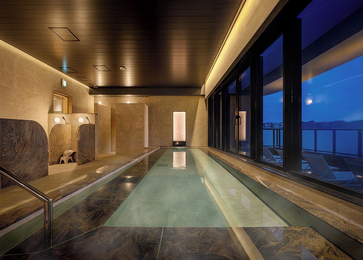 A modern indoor pool area with a view of the cityscape at dusk.