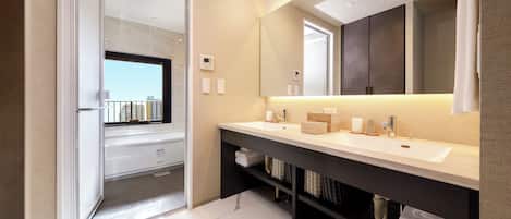 A modern bathroom with a large mirror, two sinks, a shower area, and a view through a glass door.