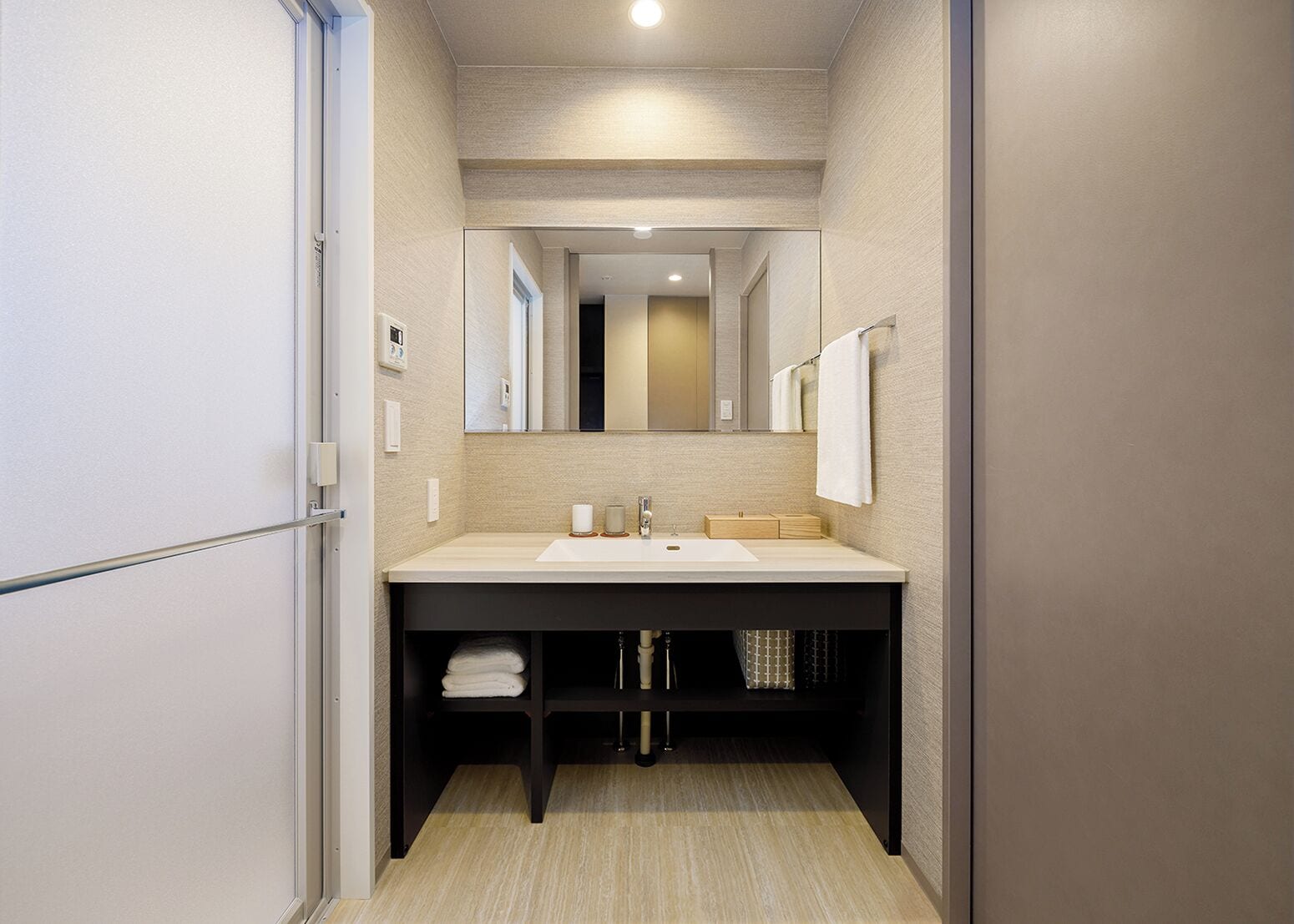 Un baño moderno con un espejo grande, un lavamanos y un perchero para toallas.