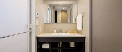 A modern bathroom with a large mirror, a sink, and a towel rack.