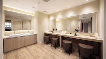 A modern bathroom with a large mirror, multiple sinks, and stools.