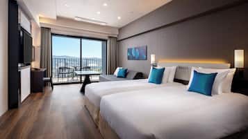 A hotel room with two beds, a TV, a balcony with a table and chairs, and a city view.