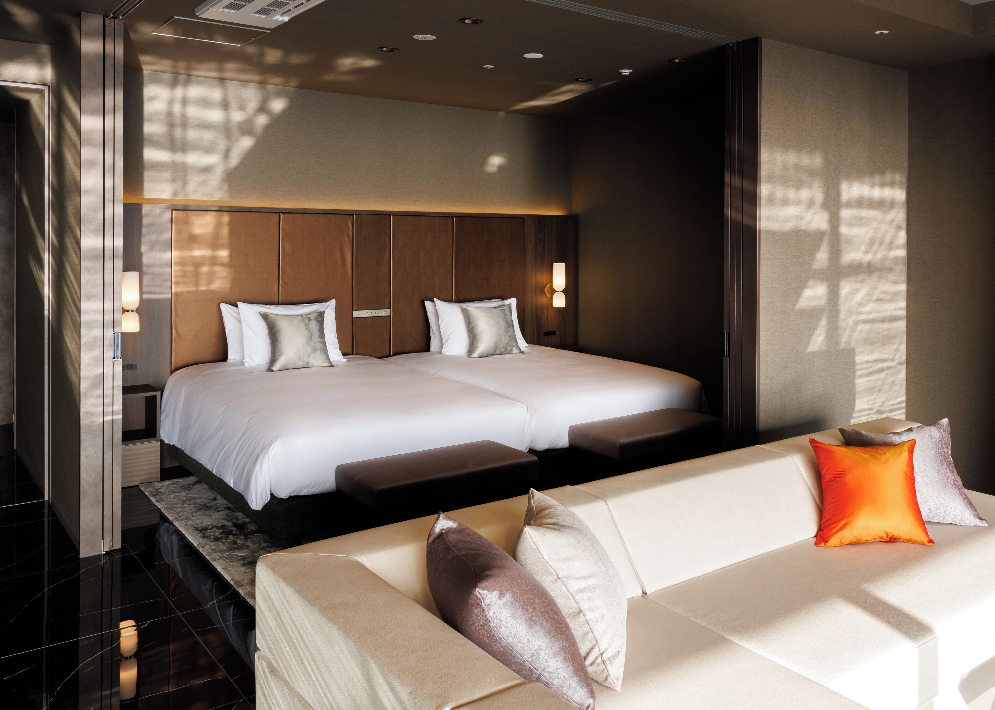 A modern hotel room with a large bed, a sofa, and a nightstand.