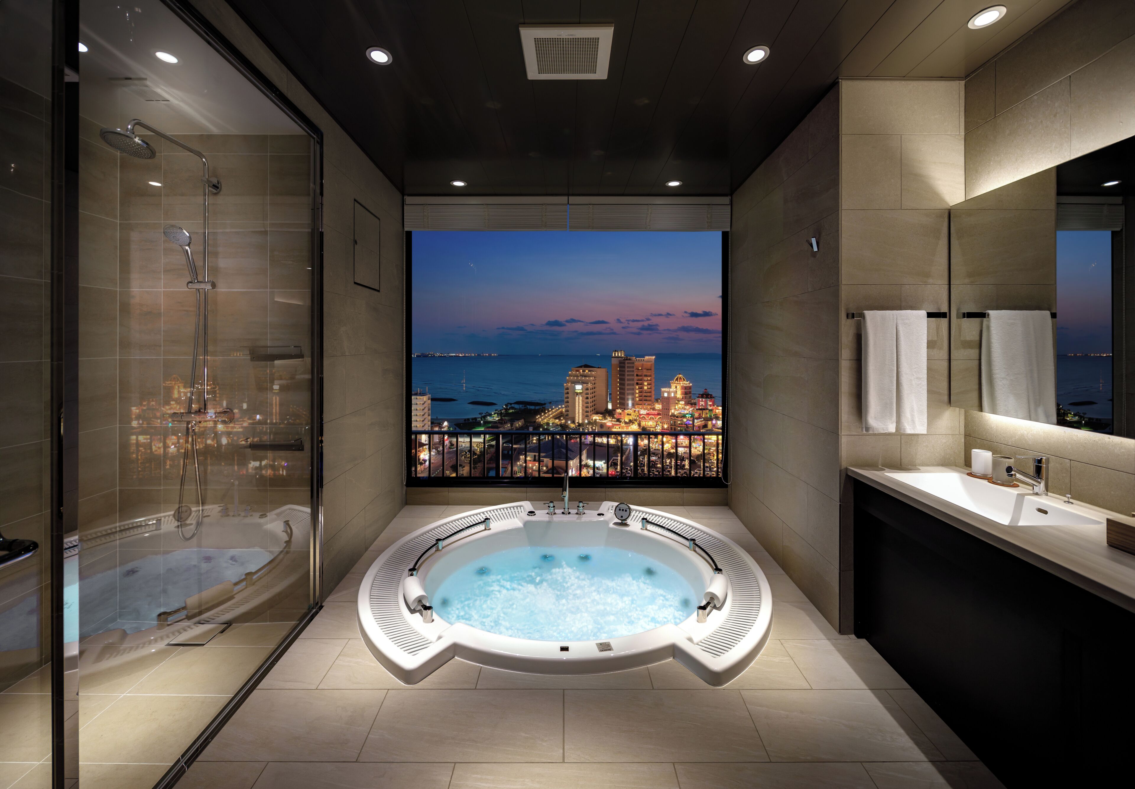 A modern bathroom with a hot tub, a shower, a balcony with a city view, and a vanity with a mirror.
