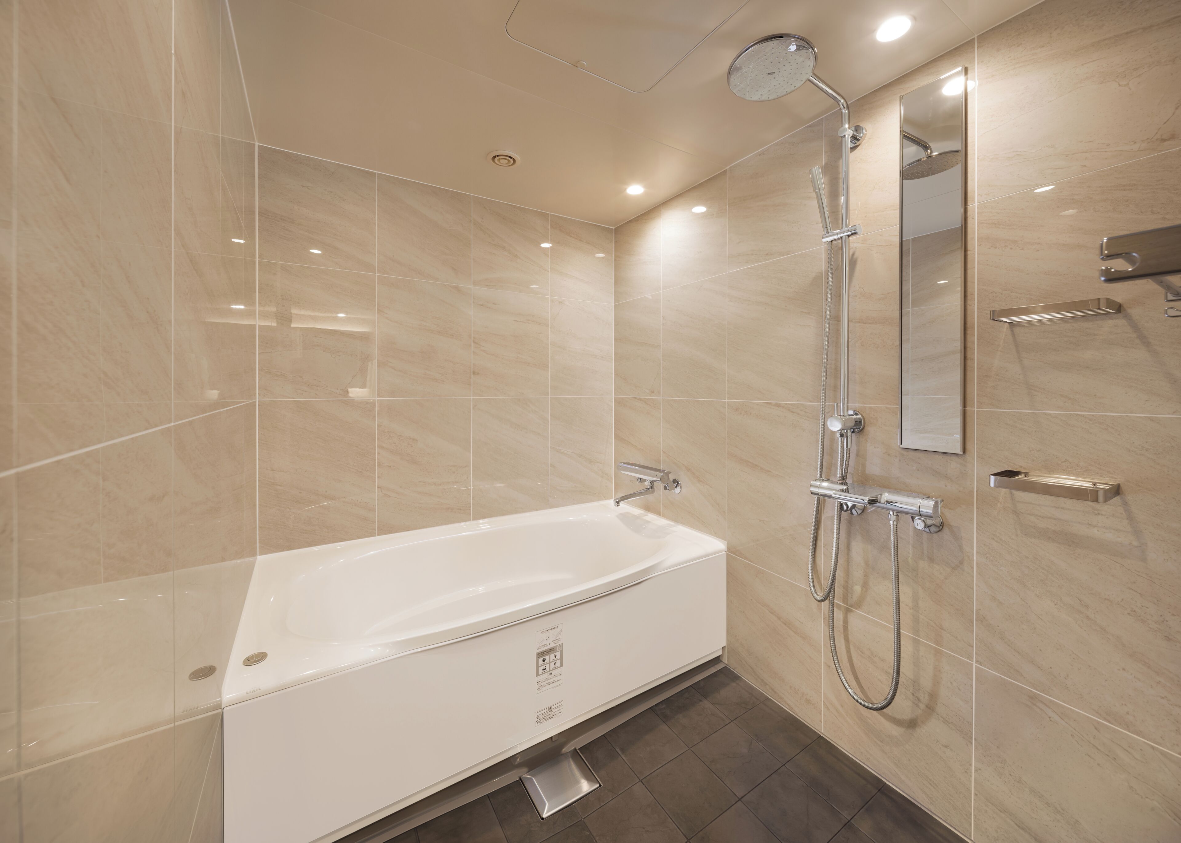 A modern bathroom with a bathtub, shower, and a mirror.