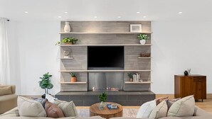Ein modernes Wohnzimmer mit großem Flachbildfernseher, Einbauschränken und Kamin.