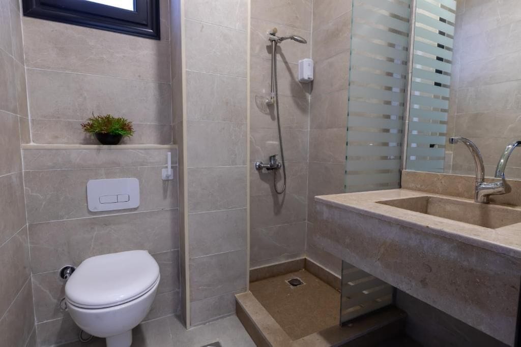 A bathroom with a toilet, a shower, and a sink.