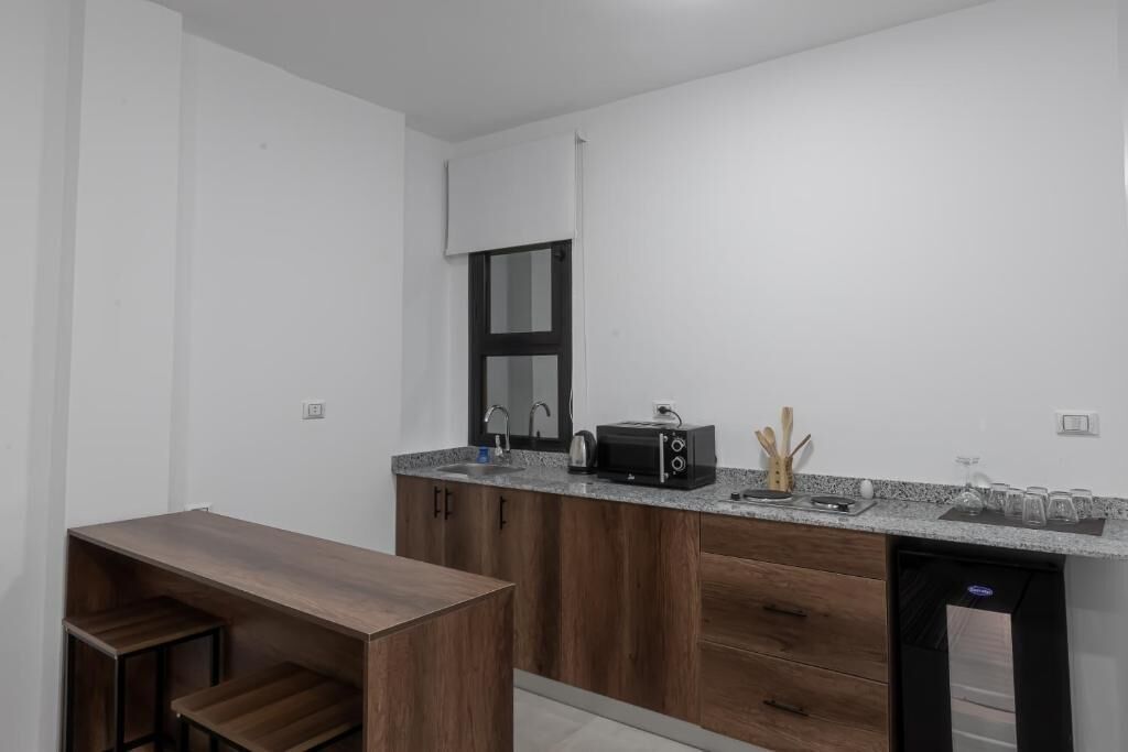 A modern kitchen with wooden cabinets, a built-in dishwasher, a countertop with a toaster, and a window above the sink.