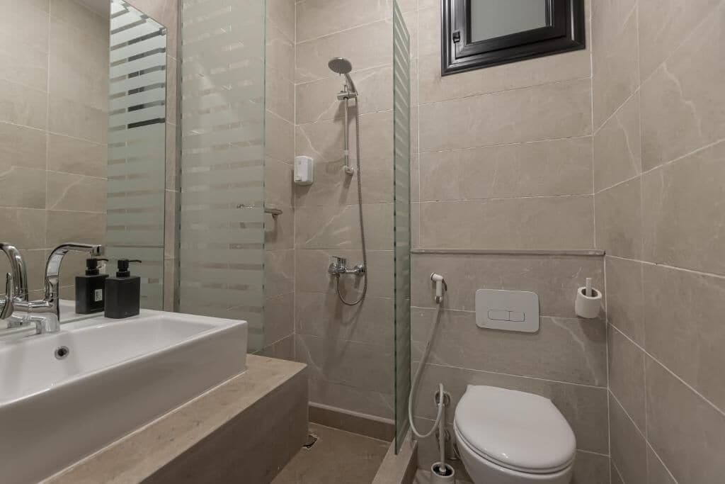 A modern bathroom with a bathtub, a toilet, and a glass-enclosed shower.