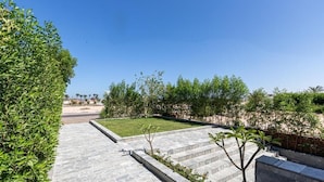 Un espacio exterior ajardinado con un sendero pavimentado, césped y setos bien recortados.