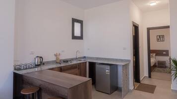 A compact kitchen with a granite countertop, a built-in dishwasher, and wooden stools.