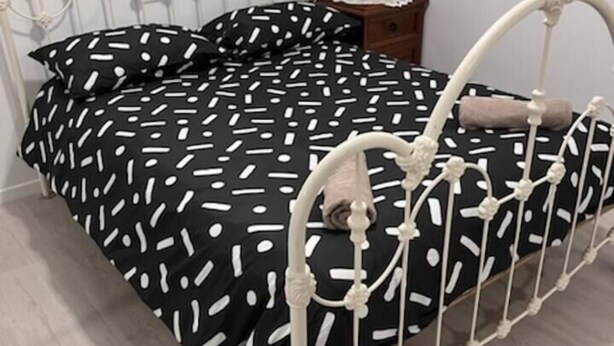 Een bed met een metalen frame en een zwart-wit stippenbedekking.