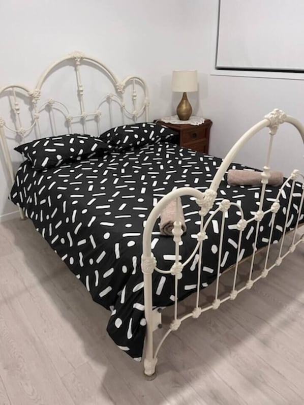 A bed with a metal frame and a black and white polka dot bedspread.