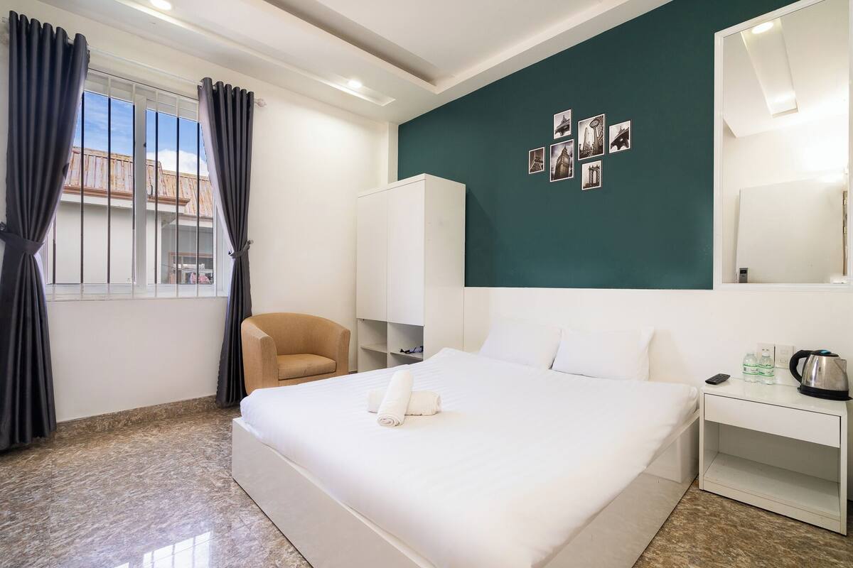 Une chambre d’hôtel avec un lit, une chaise, un bureau et un mur décoré de tableaux.