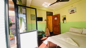 Een kamer met een bed, een plafondventilator, een televisie en een deur.