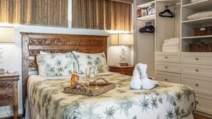 A bedroom with a bed, bedside tables, a wardrobe, and a hanging rack.