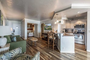 A modern kitchen with a central island, built-in appliances, and a dining area with a round table and chairs.