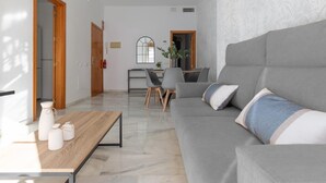 Ein modernes Wohnzimmer mit einer grauen Couch, einem Holztisch und einem Essbereich mit Stühlen und einem Tisch.