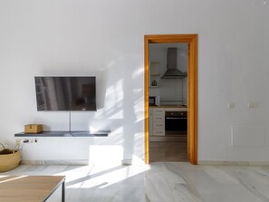 A modern kitchen with a flat-screen TV, wooden cabinet, and a tiled floor. - Urban Chic 3B - 2 dorm. Living4malaga (Distrito Centro)