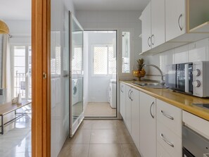 A modern kitchen with white cabinets, a wooden countertop, a microwave, and a fruit bowl. - Urban Chic 3B - 2 dorm. Living4malaga (Distrito Centro)