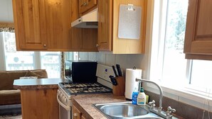 Una cocina con armarios de madera, un lavamanos de acero inoxidable y una estufa.