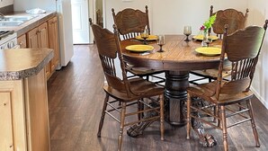 Un comedor con una mesa redonda de madera, seis sillas de madera y una lámpara colgante.