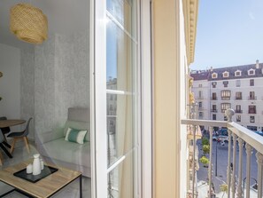 A balcony with a view of a city street, a sofa, a table with a tray, and a hanging light fixture. - Urban Chic 3A - 1 dorm Living4malaga (Distrito Centro)
