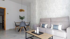 Una sala de estar moderna con un sofá, una mesa de centro, una mesa de comedor con sillas y una lámpara colgante.