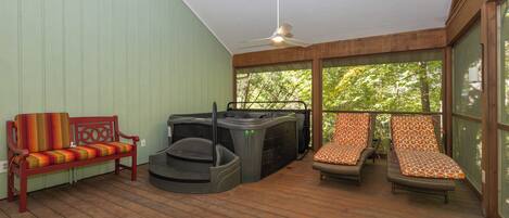 A wooden deck with a bench, a hot tub, and two lounge chairs.
