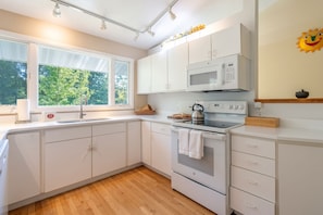 A modern kitchen with white cabinets, a stainless steel kettle, and a microwave. - Forest Hideaway- Hot tub- close to Lake Michigan (South Haven)