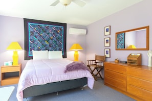 A bedroom with a bed, two bedside tables, a dresser, a chair, a mirror, and a wall with framed pictures. - Forest Hideaway- Hot tub- close to Lake Michigan (South Haven)