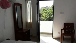 A room with a bed, a dresser, a chair, and a sliding door leading to a balcony. - Hotel City Esala (Dambulla)