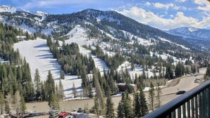 A mountain landscape with snow-covered slopes, a ski trail, and a road with vehicles. - Condo RIGHT on the Snowbird Slopes (Sandy)